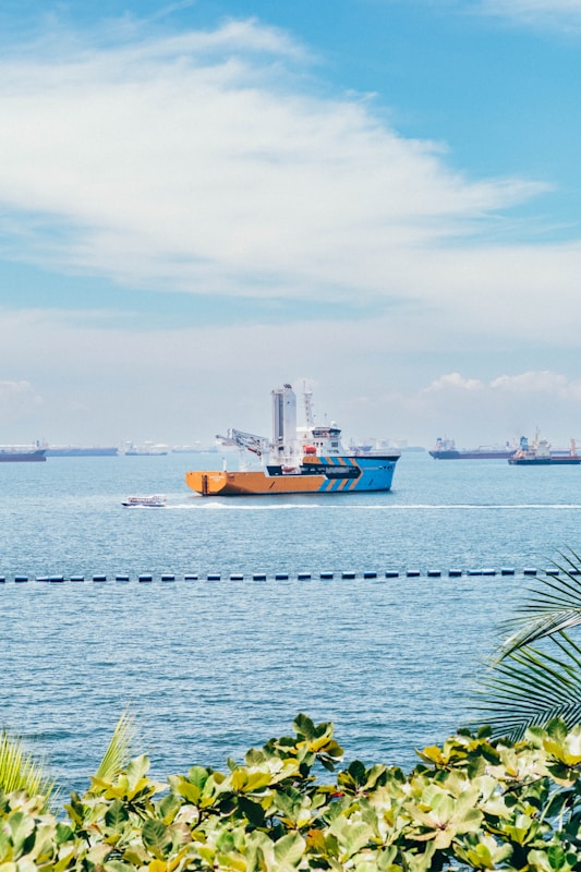 Ships at sea under a cloudy blue sky.